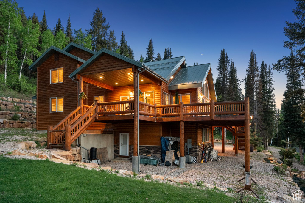 Back of house with stairs, a deck, log veneer siding, metal roof, and a lawn