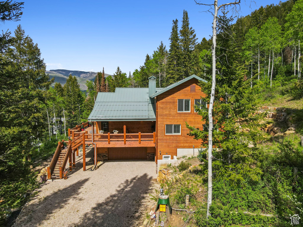 View of front of property featuring stairway, a garage, gravel driveway, metal roof, and a standing seam roof