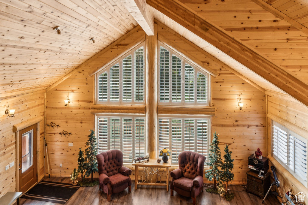 Sitting room with wood ceiling with exposed beams, wood walls, wood-type flooring, and high vaulted ceiling