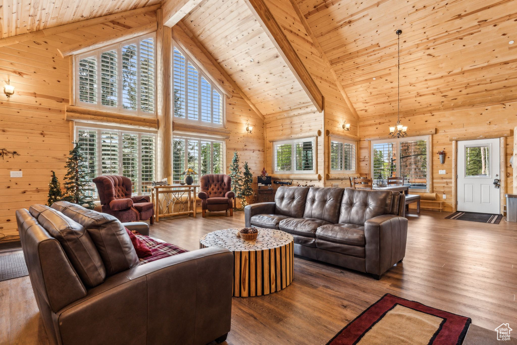 Living room featuring wood walls, high vaulted ceiling, a chandelier, wood ceiling with exposed beams, and wood finished floors