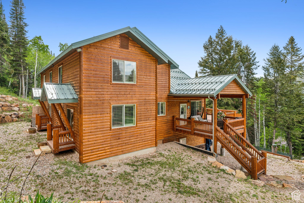 Back of property featuring stairs, metal roof, and log veneer siding