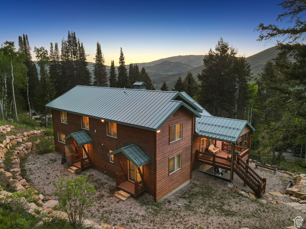 Rear view of property featuring a standing seam roof, metal roof, a mountain view, and stairway