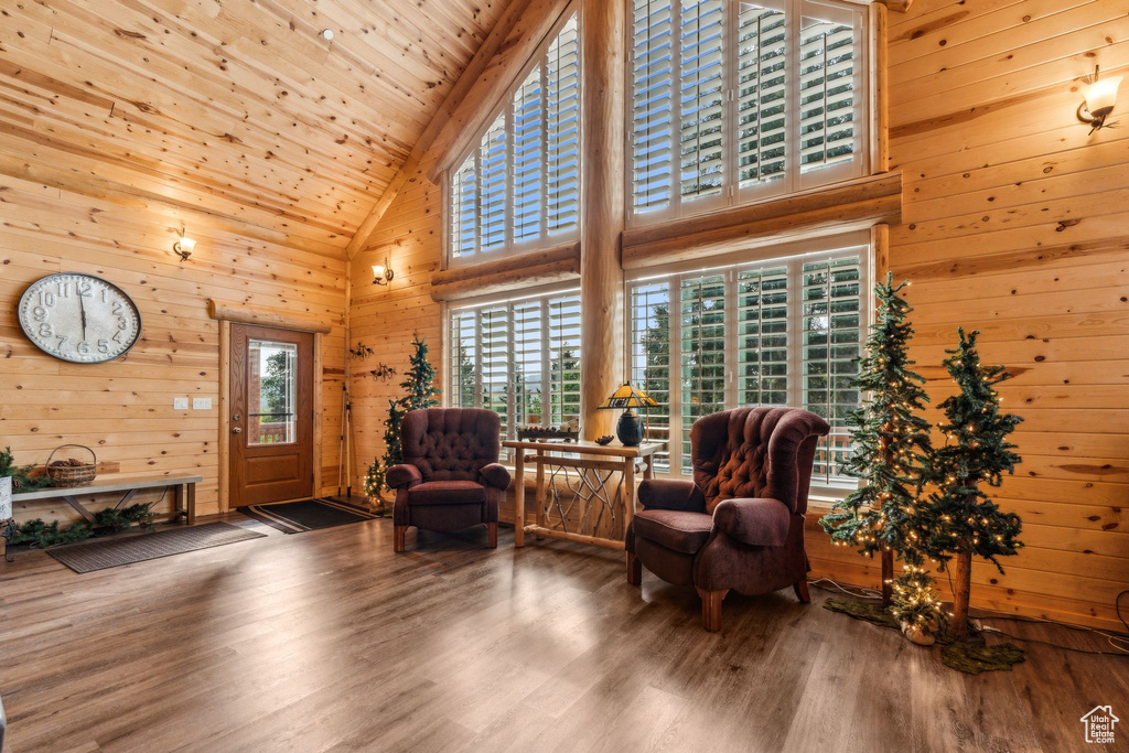 Living area with high vaulted ceiling, plenty of natural light, wooden walls, wood finished floors, and wooden ceiling
