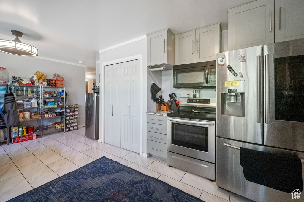 Kitchen with appliances with stainless steel finishes, light tile patterned flooring, white cabinetry, and light countertops
