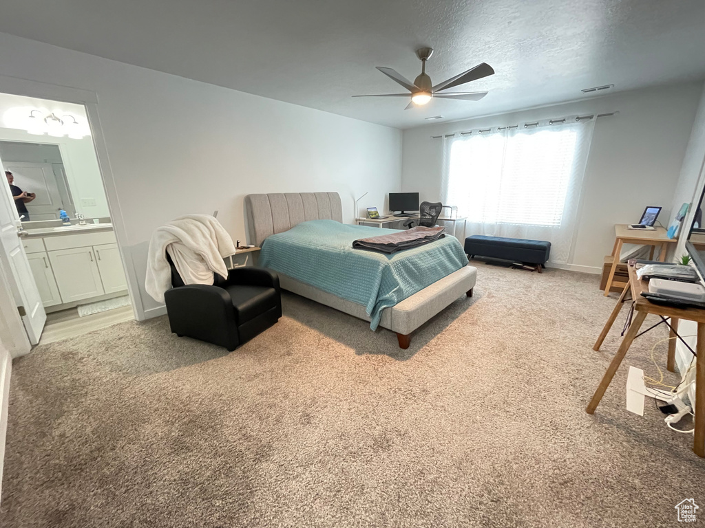 Bedroom featuring light carpet, baseboards, ensuite bath, and ceiling fan
