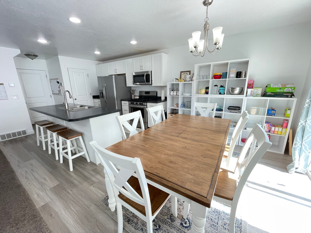 Dining space with a chandelier, light wood-style floors, recessed lighting, and a textured ceiling
