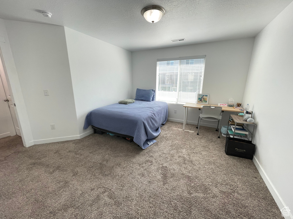 Carpeted bedroom featuring a textured ceiling and baseboards