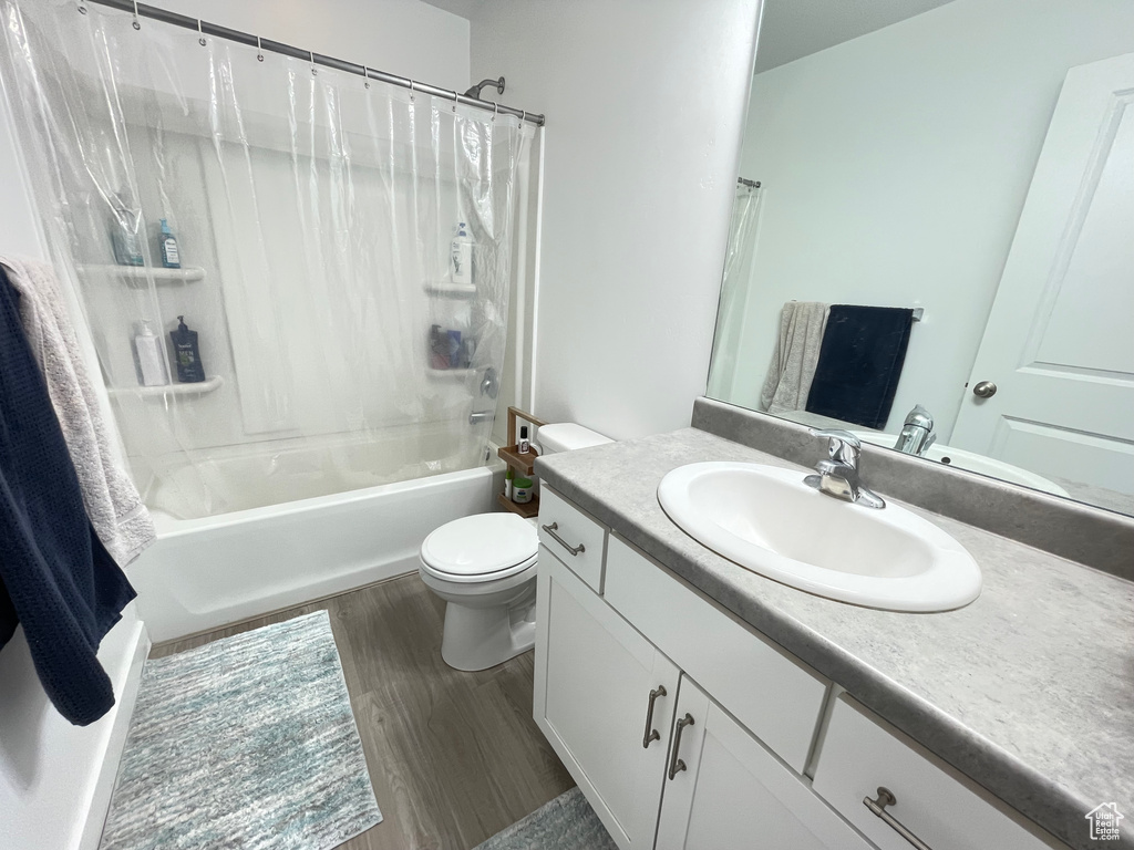 Full bath with vanity, toilet, shower / tub combo with curtain, and wood finished floors