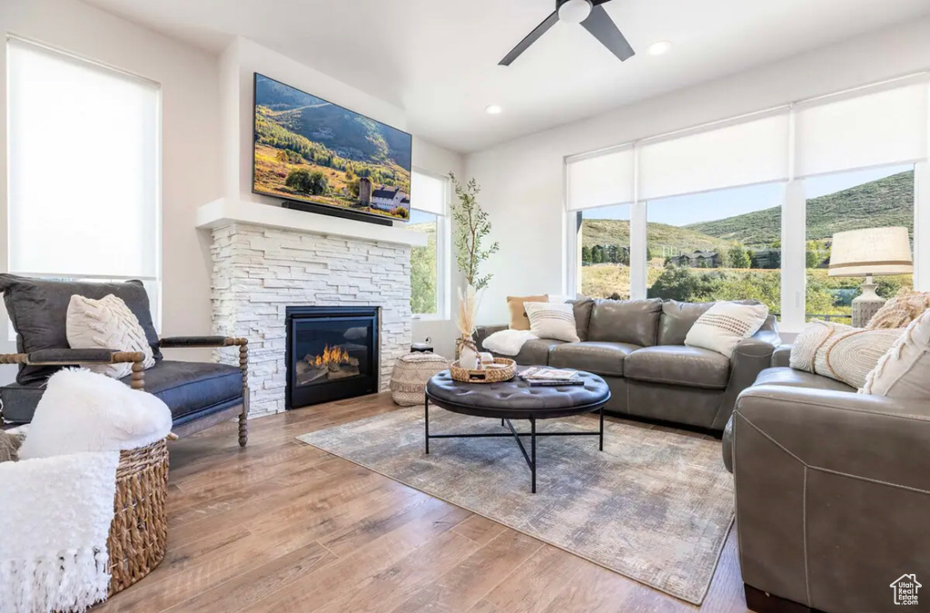 Living area featuring wood finished floors, ceiling fan, a fireplace, and recessed lighting
