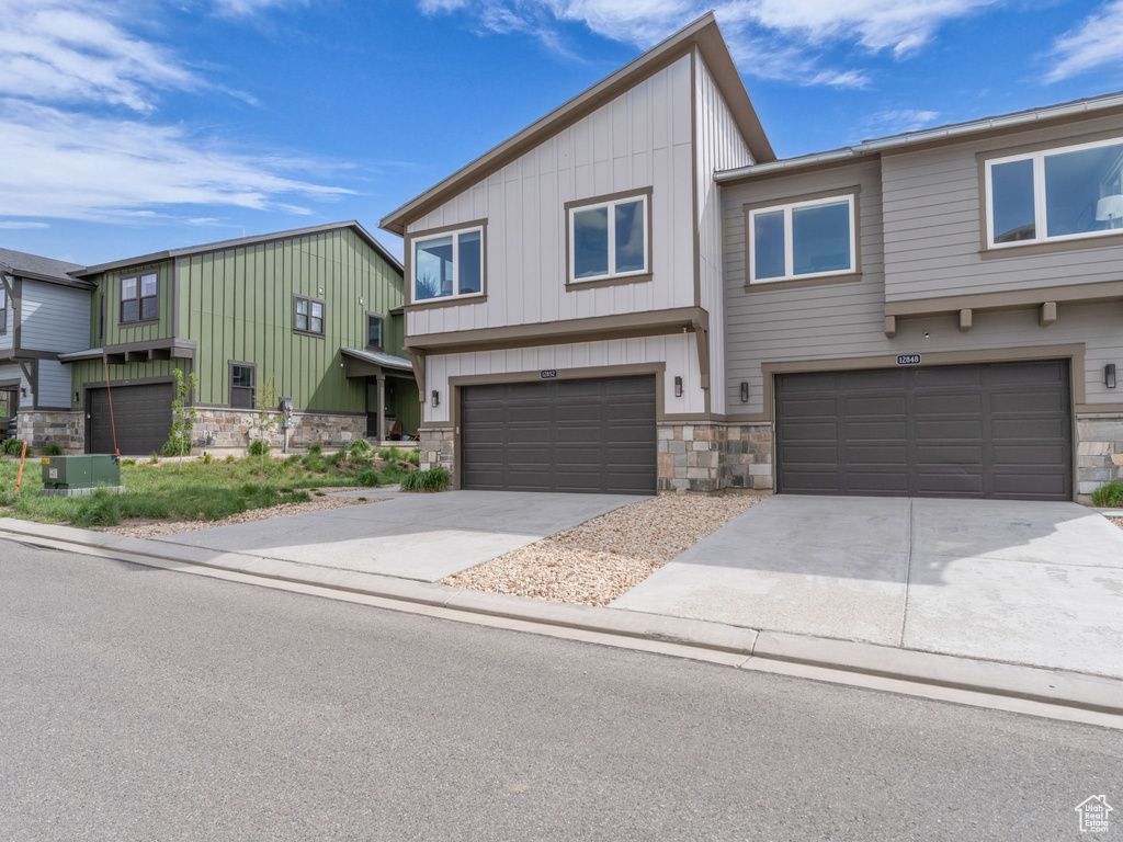 View of front of house with stone siding, an attached garage, board and batten siding, and concrete driveway