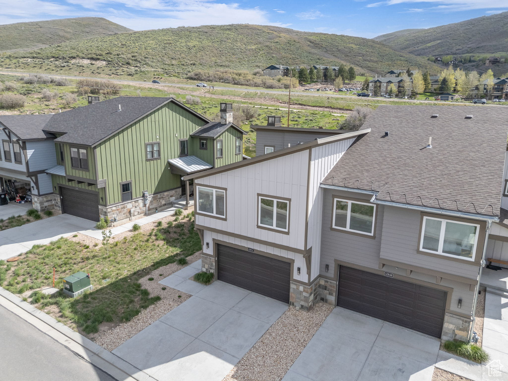 View of front facade with stone siding, an attached garage, concrete driveway, board and batten siding, and a mountain view