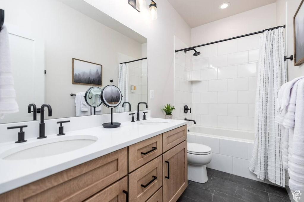 Bathroom featuring shower / bath combo with shower curtain, toilet, double vanity, tile patterned flooring, and recessed lighting