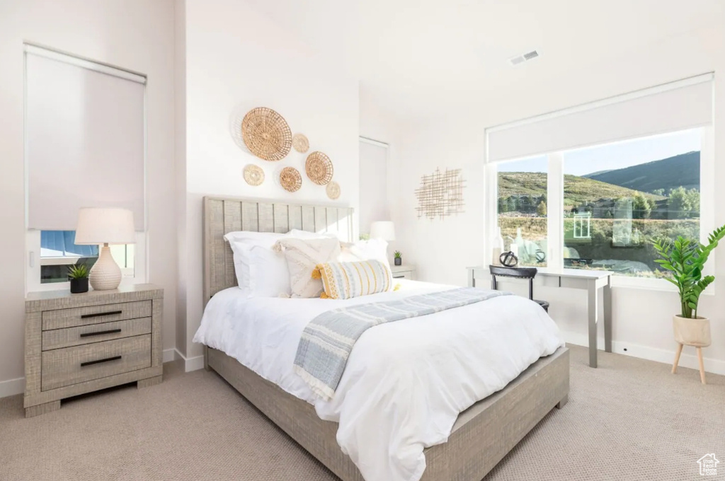Bedroom with light carpet, multiple windows, a mountain view, and baseboards