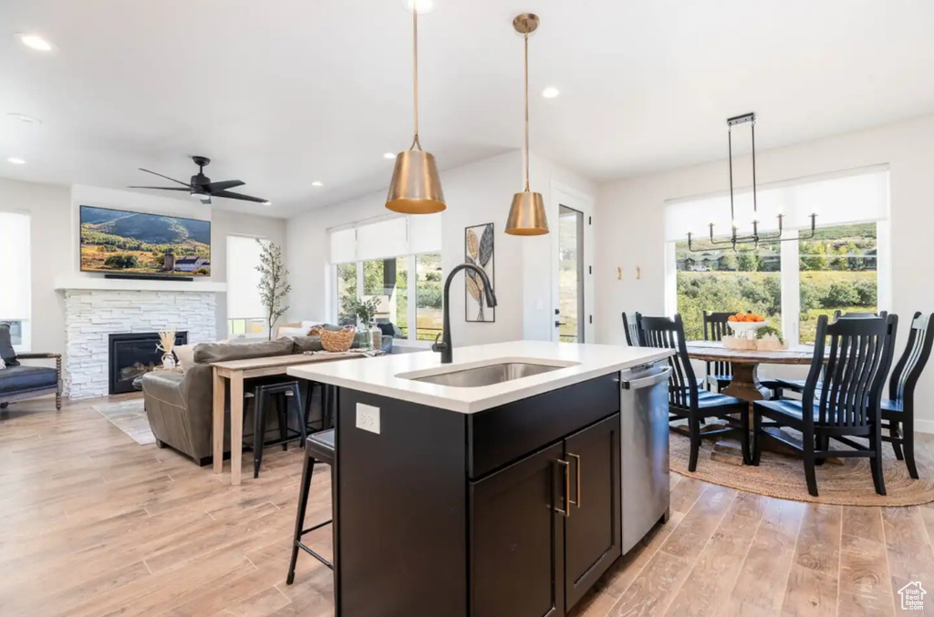 Kitchen featuring a sink, ceiling fan, light wood-style flooring, light countertops, and dishwasher