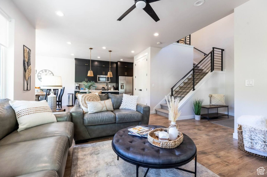 Living area with light wood finished floors, ceiling fan, stairs, recessed lighting, and baseboards