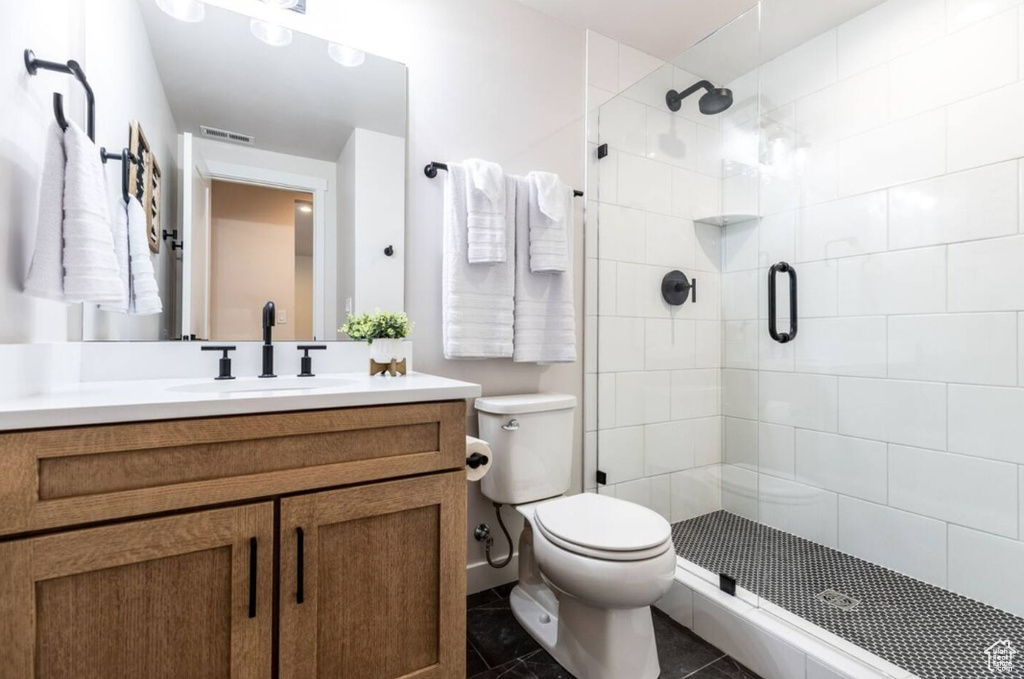 Full bathroom featuring toilet, a shower stall, vanity, and tile patterned flooring
