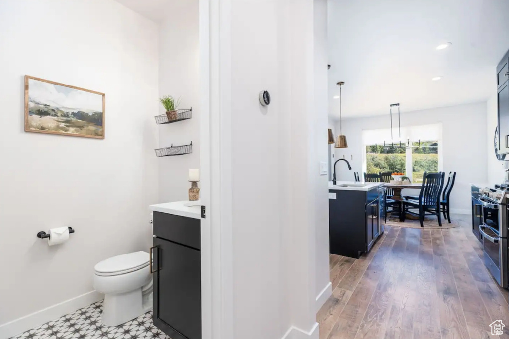 Bathroom with vanity, baseboards, toilet, recessed lighting, and wood finished floors
