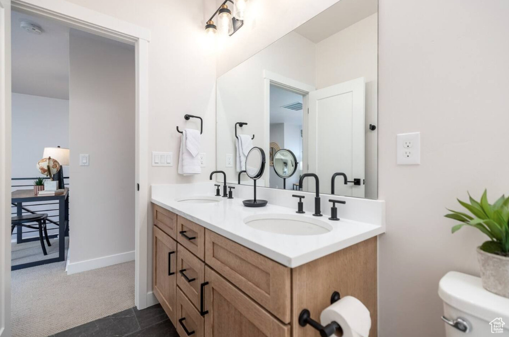 Bathroom featuring double vanity, toilet, and baseboards