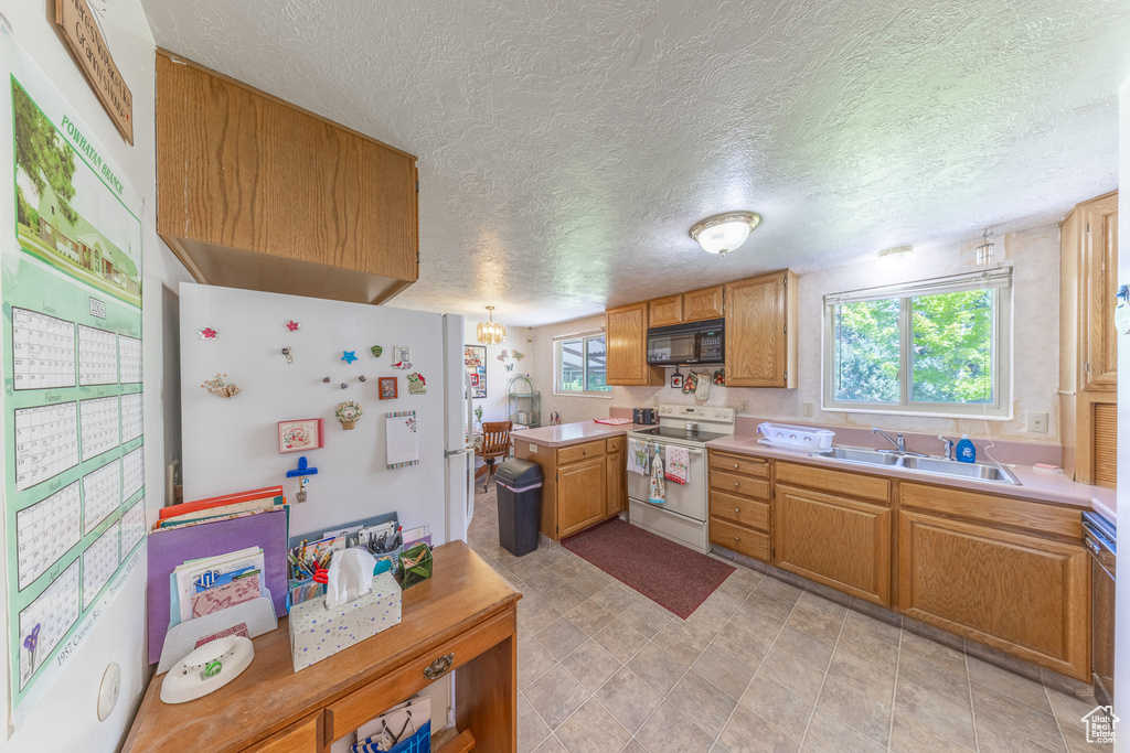 Kitchen featuring white appliances, a sink, healthy amount of natural light, light countertops, and a textured ceiling