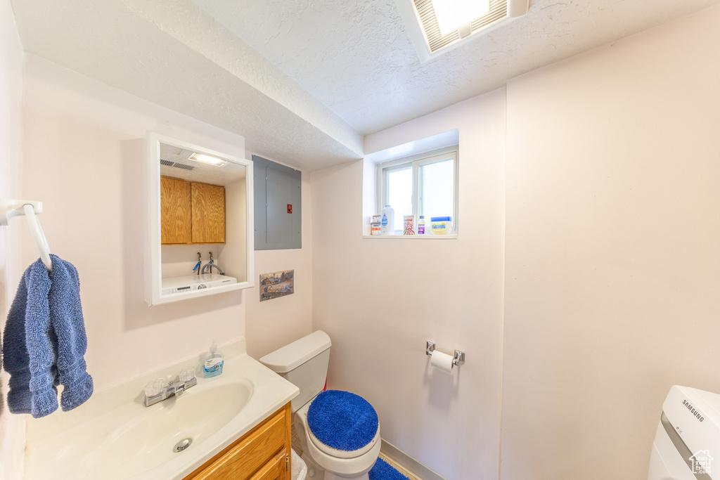 Bathroom featuring toilet, electric panel, vanity, and a textured ceiling