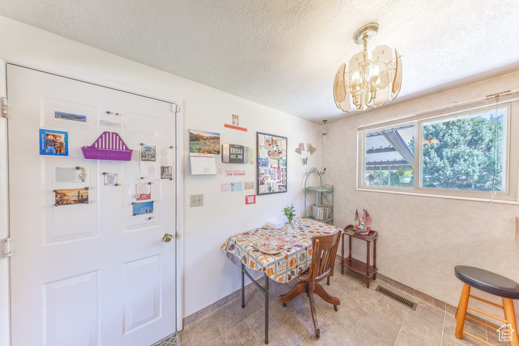 Dining space with a chandelier, a textured ceiling, and baseboards