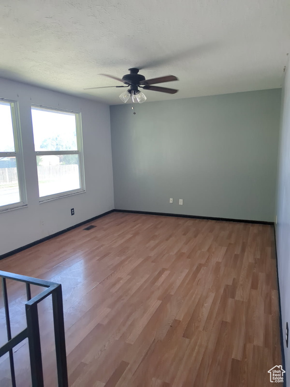 Empty room with ceiling fan and light wood finished floors
