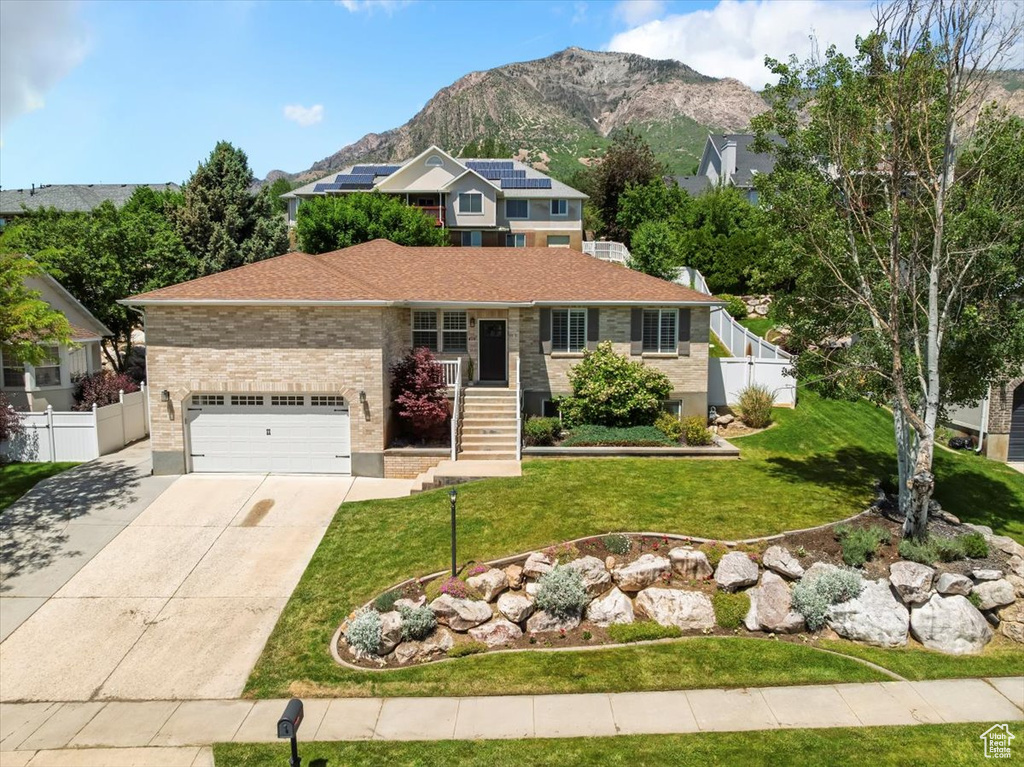 View of front of home with a garage, concrete driveway, and a mountain view