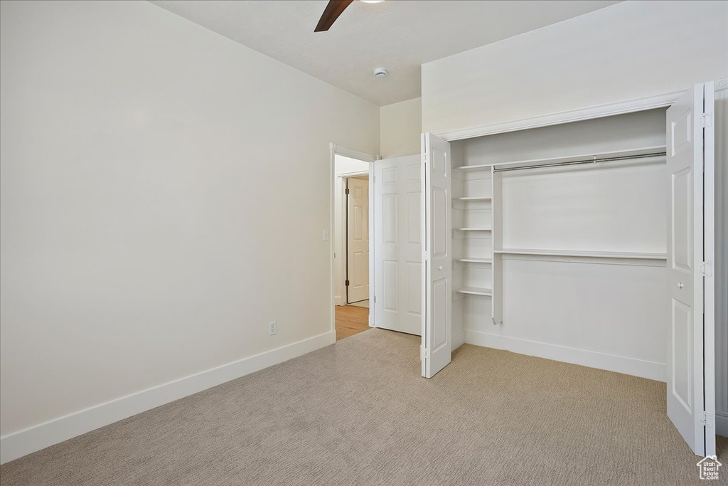 Unfurnished bedroom with light carpet, baseboards, a closet, and a ceiling fan