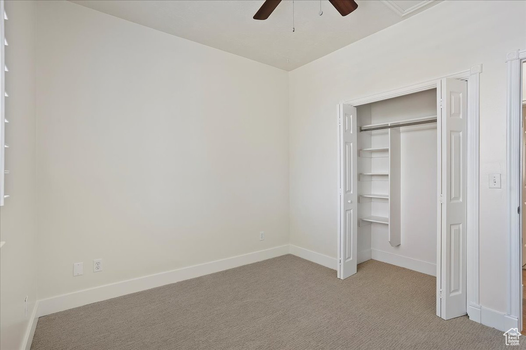 Unfurnished bedroom with light carpet, baseboards, a closet, and a ceiling fan