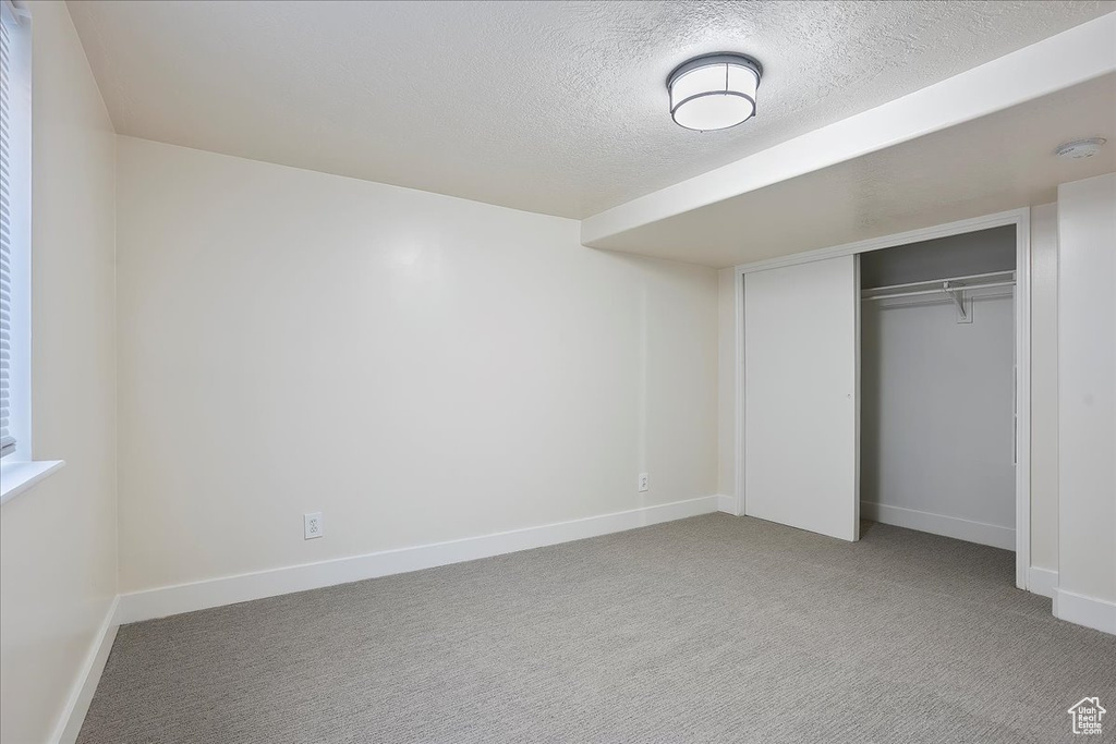 Unfurnished bedroom featuring baseboards, a closet, carpet flooring, and a textured ceiling