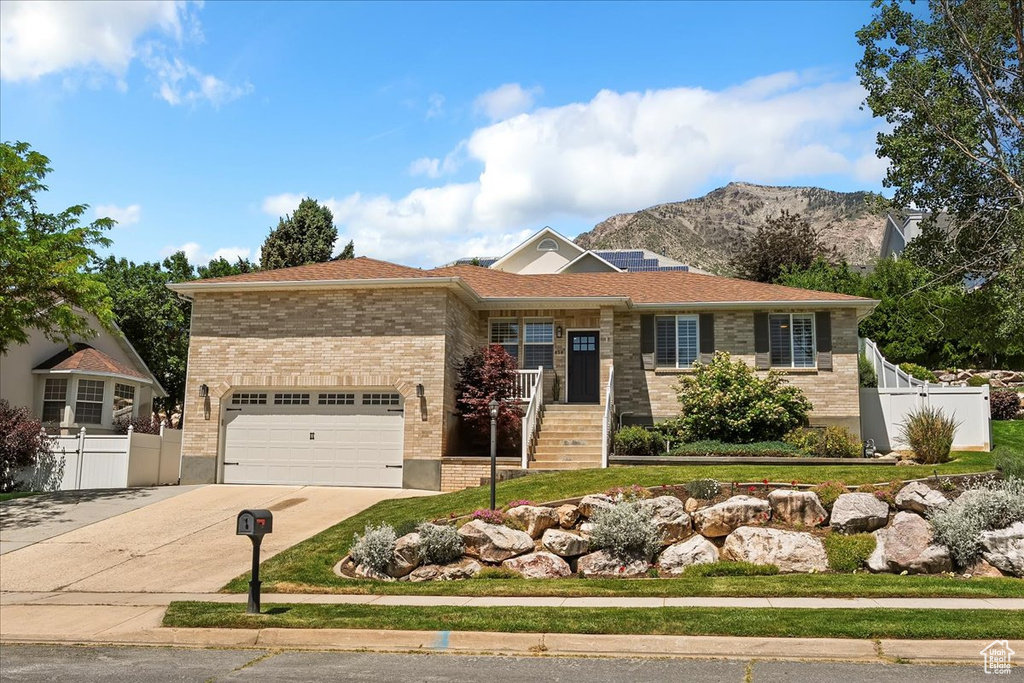 Ranch-style home featuring concrete driveway, a mountain view, brick siding, and a garage