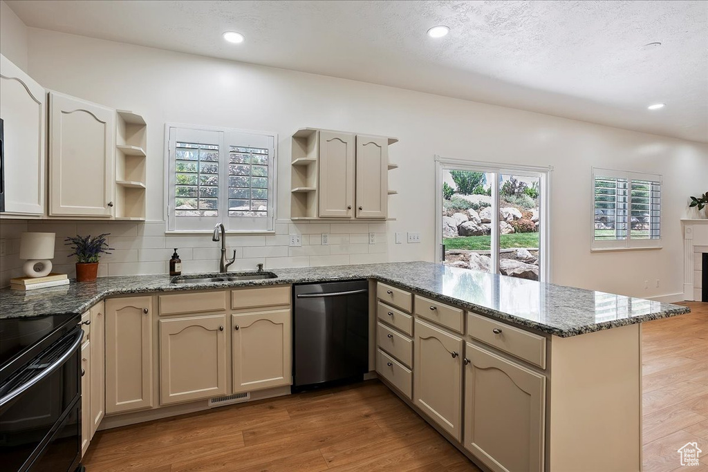 Kitchen with dishwasher, open shelves, a peninsula, a sink, and backsplash