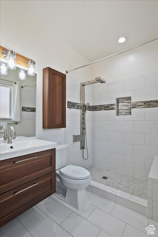 Full bathroom featuring a tile shower, vanity, toilet, and tile patterned floors