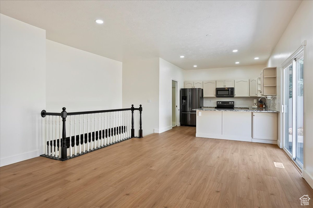 Kitchen with black appliances, open shelves, light wood-style floors, recessed lighting, and light stone counters