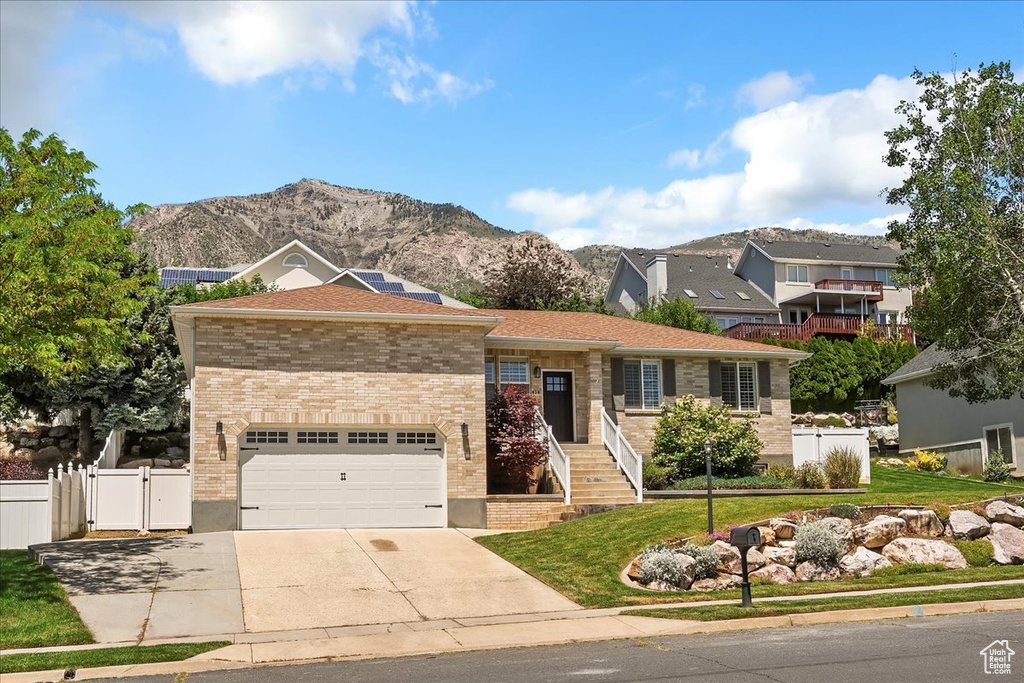 View of front of home featuring driveway, a mountain view, a gate, and brick siding