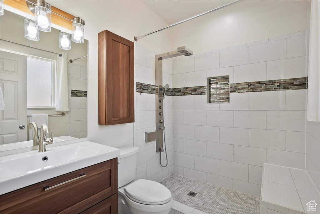Full bath with a tile shower, toilet, and vanity