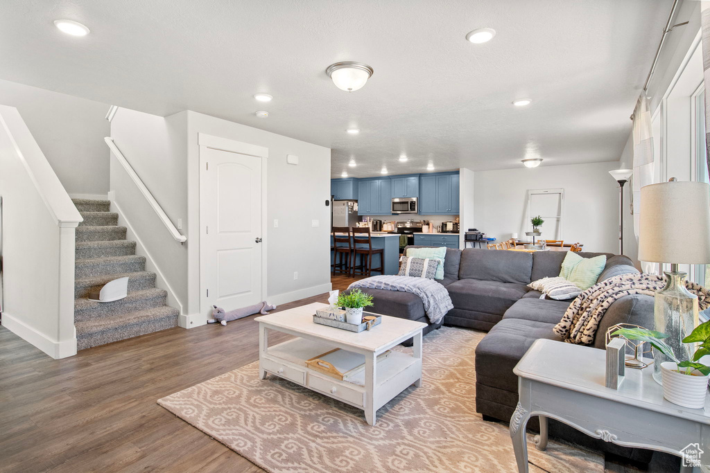 Living area featuring wood finished floors, recessed lighting, stairs, and baseboards