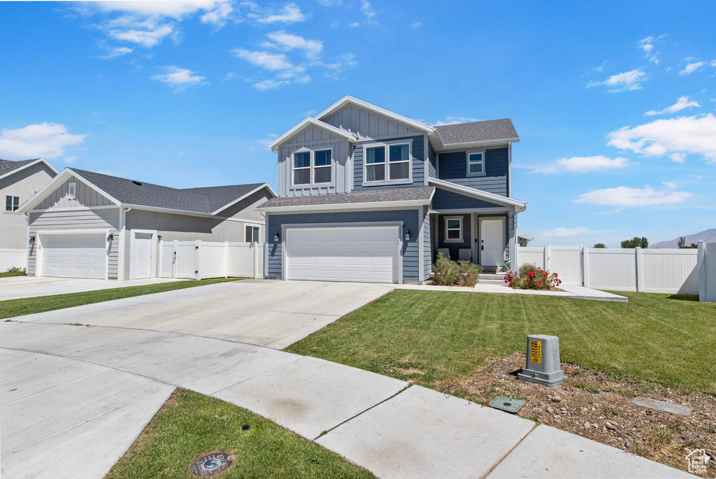 View of front of home with board and batten siding, driveway, a garage, and a gate