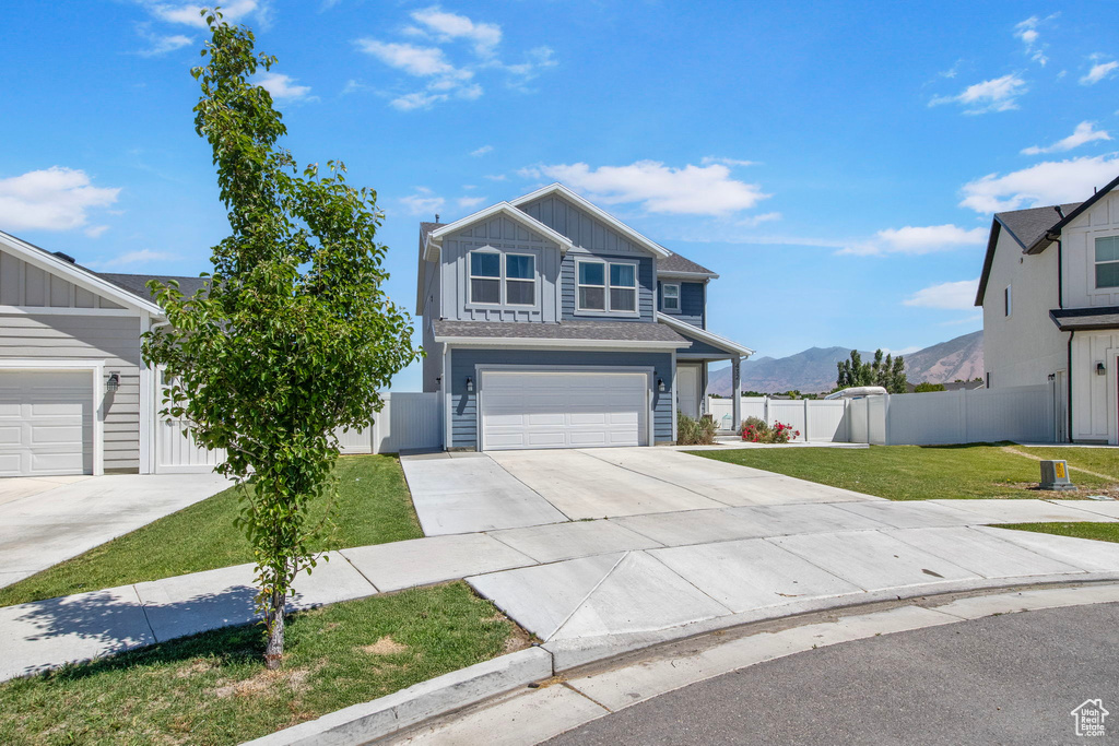 View of front of home with board and batten siding, driveway, a mountain view, and a garage