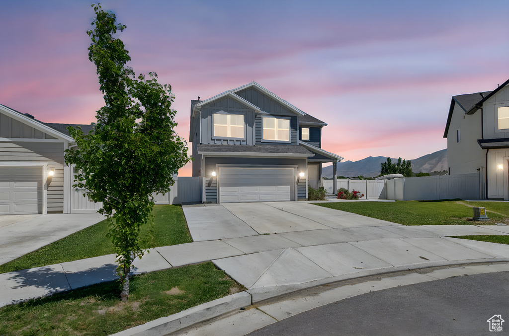 View of front facade with concrete driveway, board and batten siding, a garage, and a mountain view