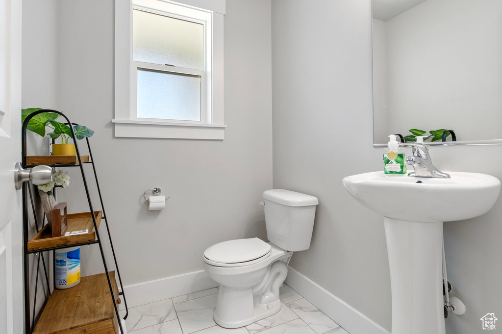 Half bathroom featuring toilet, baseboards, and marble look tile flooring