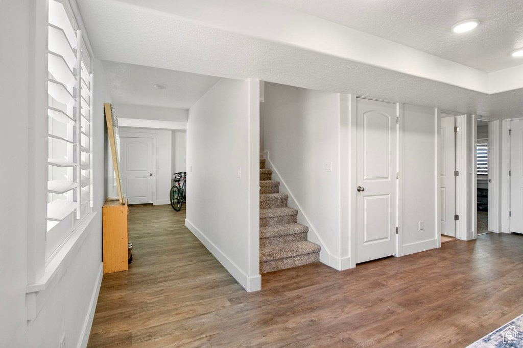 Entryway with baseboards, wood finished floors, stairs, a textured ceiling, and recessed lighting