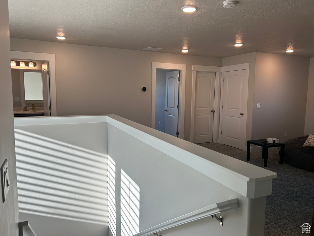 Corridor with carpet, a textured ceiling, recessed lighting, and an upstairs landing