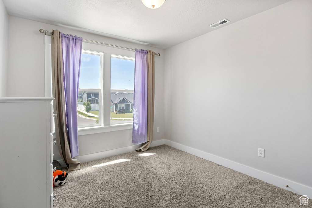 Carpeted spare room featuring baseboards