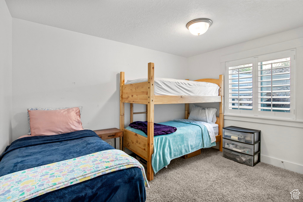 Carpeted bedroom with a textured ceiling and baseboards