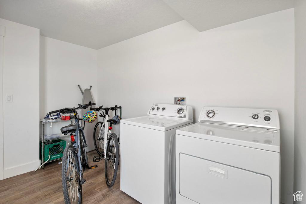 Laundry area featuring washing machine and dryer, wood finished floors, and baseboards