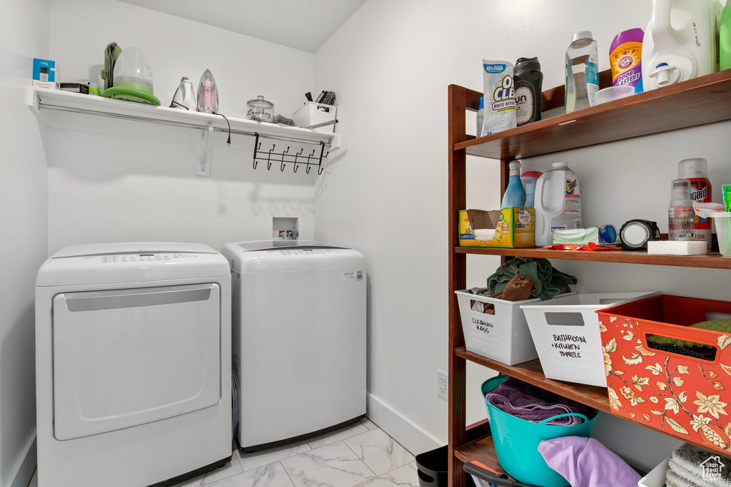 Laundry area with independent washer and dryer, light marble finish flooring, and baseboards