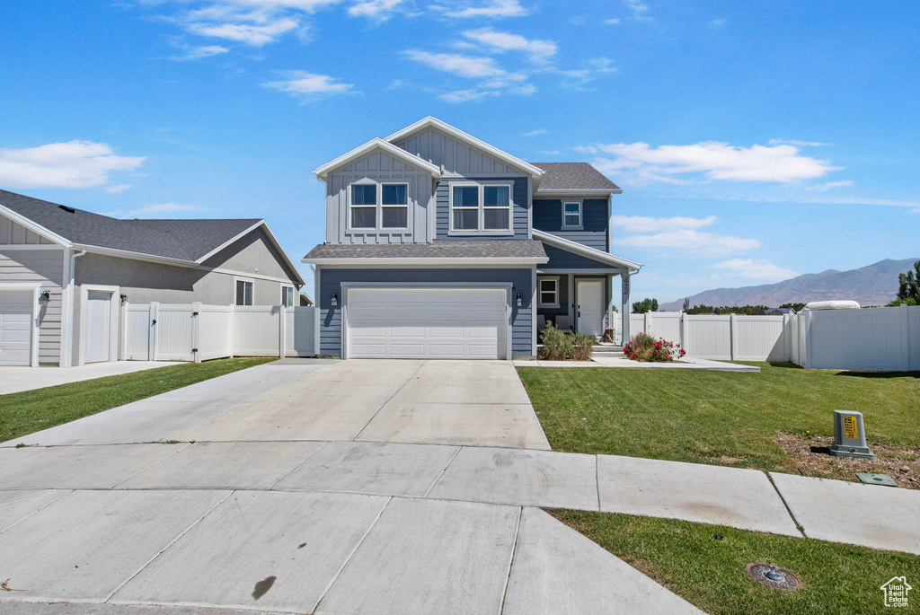 View of front of house with a gate, driveway, board and batten siding, a garage, and a mountain view