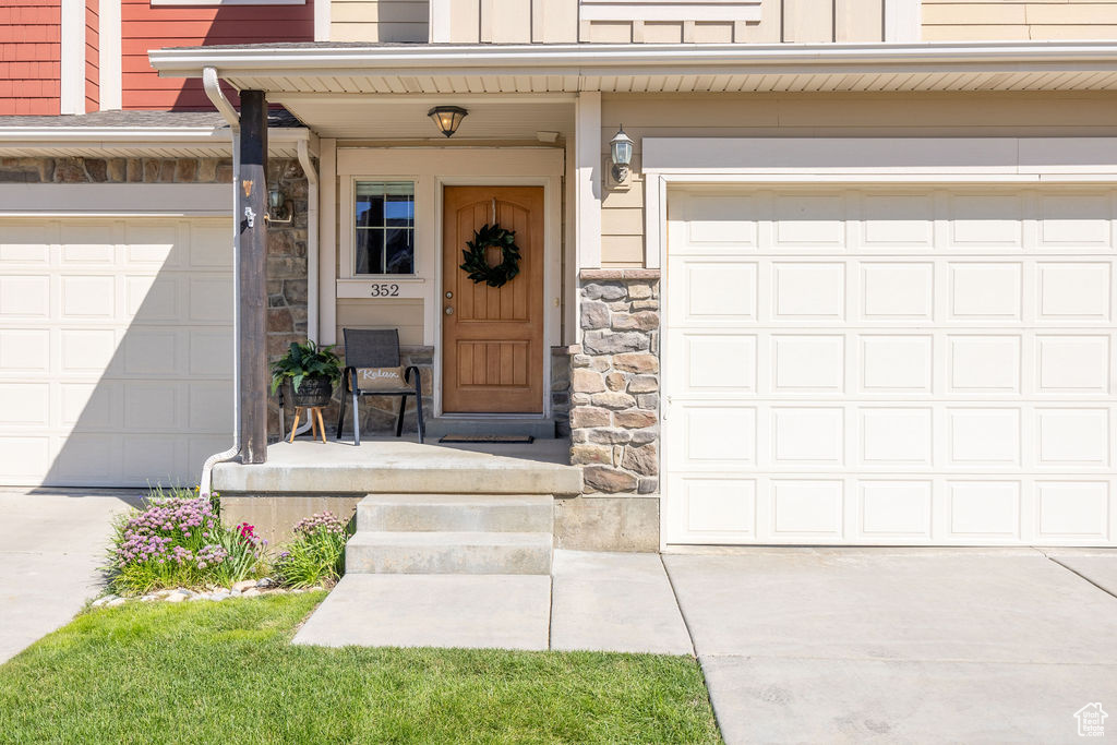 Entrance to property featuring driveway, board and batten siding, stone siding, and covered porch