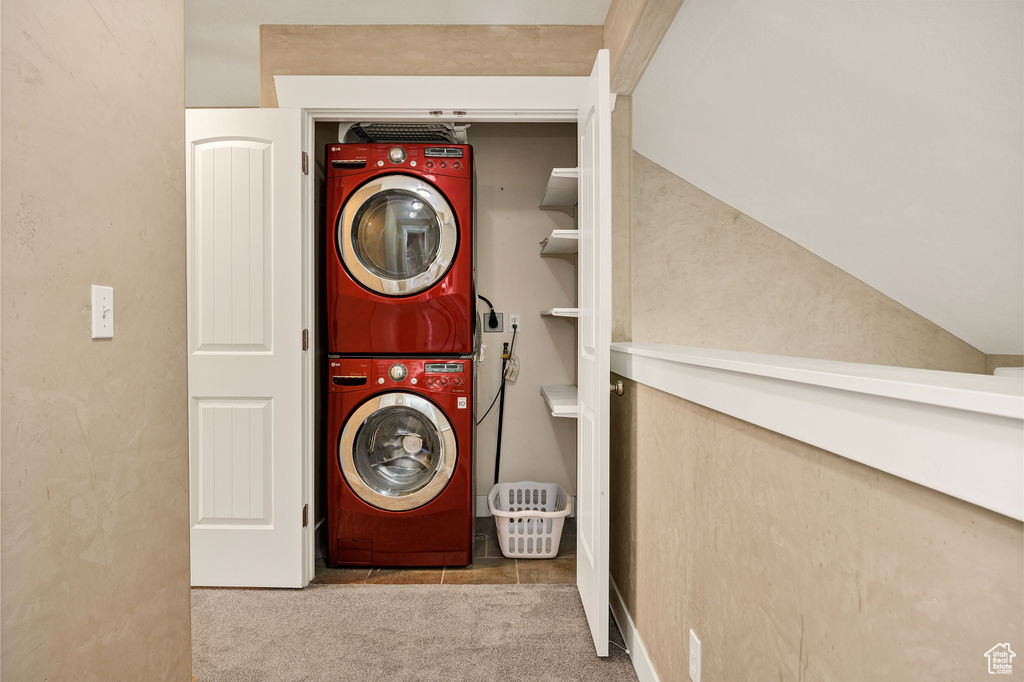 Laundry area featuring stacked washer / drying machine and carpet floors